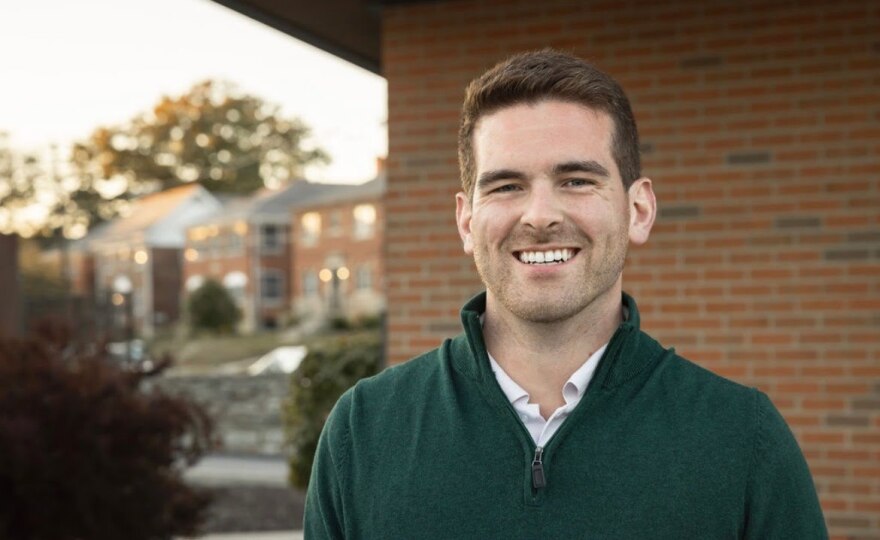 Seth Walsh smiling in a green quarter-zip outside a brick building